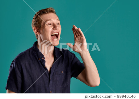 Close-up portrait of a ginger guy in navy t-shirt posing on blue background. Sincere emotions. Close-up portrait of a ginger guy in navy t-shirt posing on blue background. Sincere emotions. 89940146