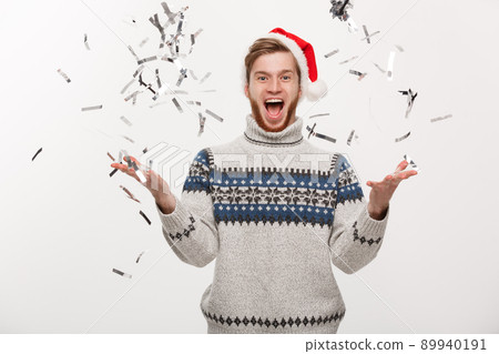 Chirstmas Concept - Happy young caucasian beard man throwing confetti celebrating for Christmas day. 89940191