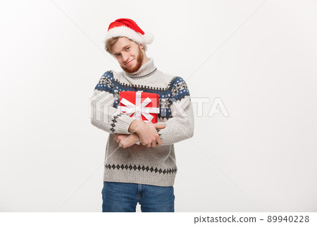 Christmas Concept - Happy young man with beard carries present isolated on white background. 89940228
