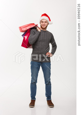 Christmas Concept - Young handsome beard man happy with shopping bag in the hand isolated on white. 89940516