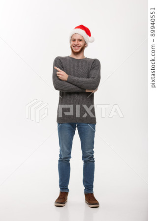 Holiday Concept - Young beard man in sweater enjoy playing and pointing finger onside with copyspace. 89940551