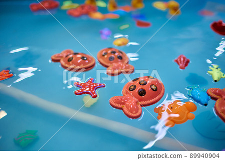 Multicolored plastic toy fish in pool for children's fishing, concept game. 89940904
