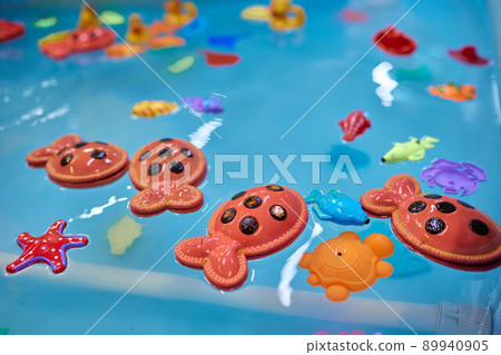 Multicolored plastic toy fish in pool for children's fishing, concept game. Multicolored plastic toy fish in pool for children's fishing, concept game. 89940905