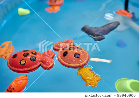 Multicolored plastic toy fish in pool for children's fishing, concept game. Multicolored plastic toy fish in pool for children's fishing, concept game. 89940906