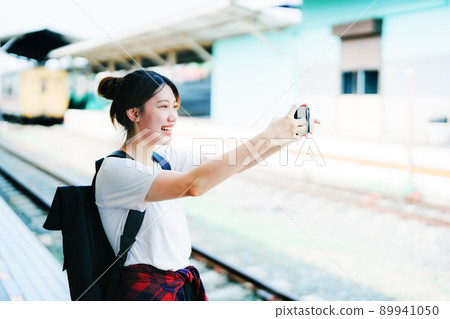 summer, relax, vacation, travel, portrait of beautiful Asian girl using the smartphone mobile take a photo selfie face yourself at the train station while waiting for their travel time 89941050