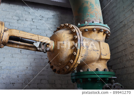 Close-up at pipeline valve which is using to control production process in the oil refinery plant. Selective focus at the valve handle wheel, Heavy industrial object photo. 89941270