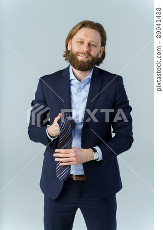 a handsome brutal bearded and long-haired man, the man took off his tie and held it in his hands, a stylish businessman on a white background a handsome brutal bearded and long-haired man, the man took off his tie and held it in his hands, a stylish businessman on a white background 89941488