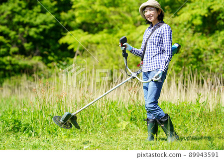 Middle-aged woman mowing with a mower 89943591