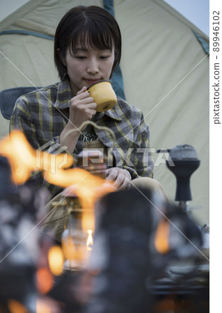Bonfire and young women outdoor solo camp chairing 89946102