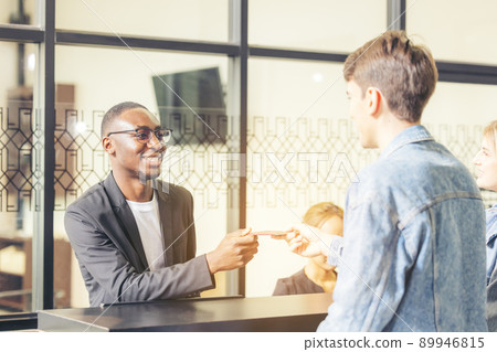 Guests handing their check-in information to the hotel receptionist with a smile Guests handing their check-in information to the hotel receptionist with a smile 89946815