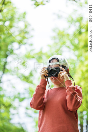Woman holding a camera in the park 89948411