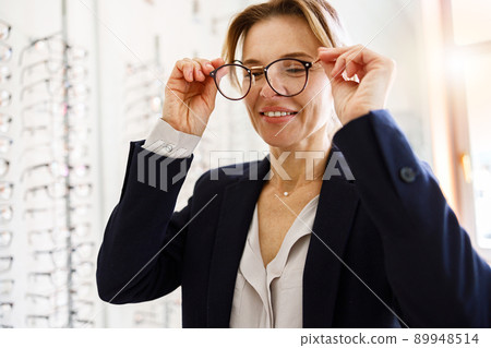 Woman client takes off the glasses that did not fit her in ophthalmic store Woman client takes off the glasses that did not fit her in ophthalmic store 89948514