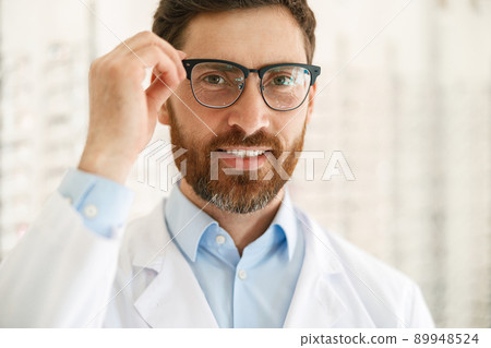 Portrait of smiling ophthalmologist in front of showcase in optics store Portrait of smiling ophthalmologist in front of showcase in optics store 89948524