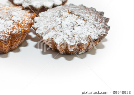 Small sweet cupcakes sprinkled with sugar sprinkles on a white background. 89948938