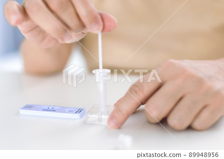 Woman using covid-19 rapid antigen test kit home 89948956