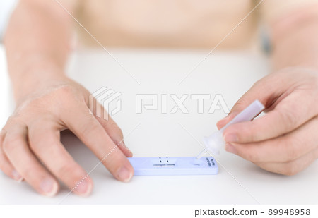 Woman using covid-19 rapid antigen test kit home 89948958