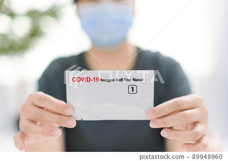 Woman using covid-19 rapid antigen test kit home 89948960