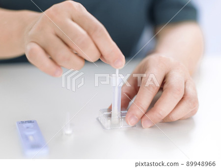 Woman using covid-19 rapid antigen test kit home 89948966