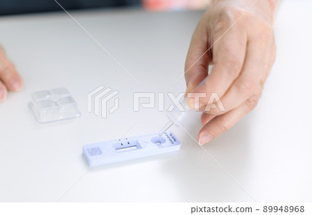 Woman using covid-19 rapid antigen test kit home 89948968