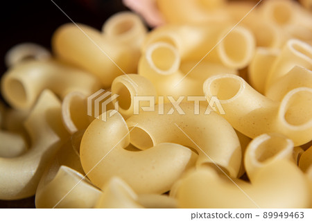Pasta, curved hollow horns. Background for the culinary theme. Pasta, curved hollow horns. Background for the culinary theme. 89949463