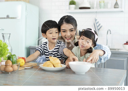 Happy Asian mother with son and daughter in kitchen. Enjoy family activity together. 89950013