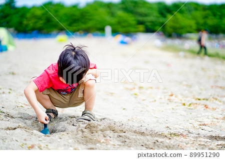 A child playing by digging a hole in the sandy beach A child playing by digging a hole in the sandy beach 89951290