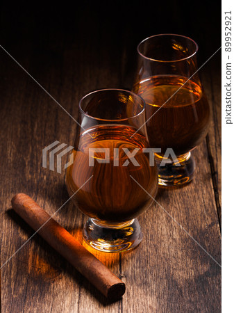 Single malt scotch whiskey in glencairn glasses with cuban cigar on wooden table 89952921