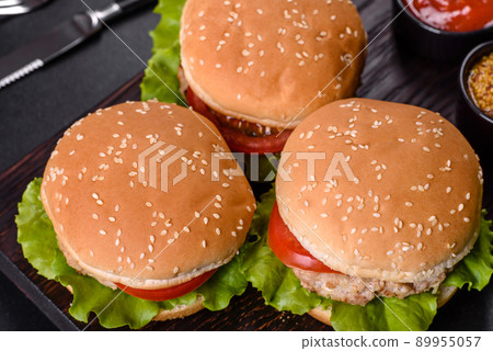 Three hamburger with beef meat burger and fresh vegetables on dark background Three hamburger with beef meat burger and fresh vegetables on dark background 89955057