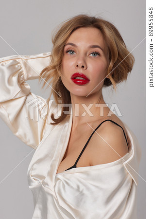 Beautiful stunning woman with red full lips, smokey eyes make up , shining perfect wavy hairs in elegant casual black dress posing on white background. 89955848