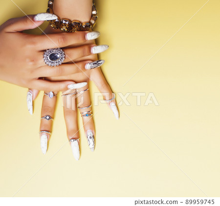 woman hands holding colorful paper copyspace wearing a lot of jewelry and long nails closeup 89959745