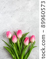 Bouquet blooming pink tulips flowers with green leaves on gray concrete background flat lay with copy space for congratulations, advertising or design. Minimalism concept. 89960573
