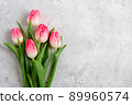 Bouquet blooming pink tulips flowers with green leaves on gray concrete background flat lay with copy space for congratulations, advertising or design. Minimalism concept. 89960574