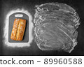 Top view of baking dark background withwith fresh whole loaf of bread and flour applied to place under the text and along contour of cutting board. 89960588