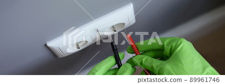Hands in gloves measure the voltage in the outlet with a tool Hands in gloves measure the voltage in the outlet with a tool 89961746