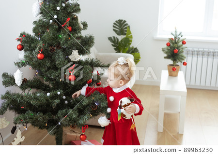 Toddler child with cochlear implant decorating christmas tree - deafness and innovating medical technologies for hearing aid 89963230