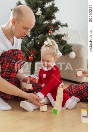 Toddler child with cochlear implant plays with parents under christmas tree - deafness and innovating medical technologies for hearing aid Toddler child with cochlear implant plays with parents under christmas tree - deafness and innovating medical technologies for hearing aid 89963232