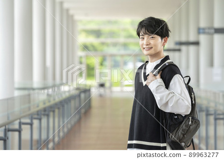 A young man with a backpack looking at the camera and smiling A young man with a backpack looking at the camera and smiling 89963277