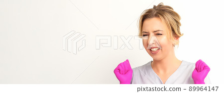 Happy caucasian woman doctor wearing pink gloves celebrates and raising fists on white background Happy caucasian woman doctor wearing pink gloves celebrates and raising fists on white background 89964147