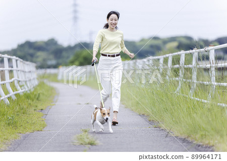 A young lady walking a dog 89964171