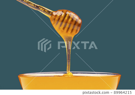 fresh honey drips from a spoon into a plate. organic vitamin health food 89964215