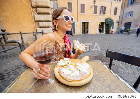 Woman eating pizza at italian restaurant outdoors 89965365