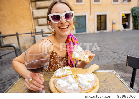 Woman eating pizza at italian restaurant outdoors 89965366