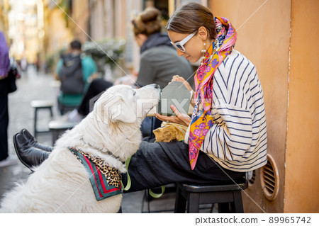 Woman cares her dog while eating pasta at outdoors cafe 89965742
