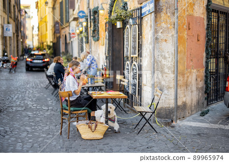 Woman sitting at traditional restaurant on the beautiful cozy street in Rome Woman sitting at traditional restaurant on the beautiful cozy street in Rome 89965974