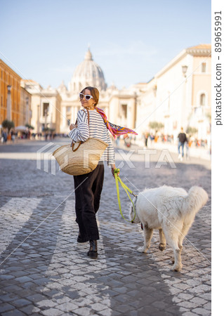 Stylish woman walks with a dog on the street in Rome Stylish woman walks with a dog on the street in Rome 89965991