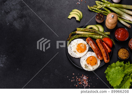A delicious nourishing breakfast with fried eggs, sausages, asparagus, tomatoes, avocado, spices and herbs A delicious nourishing breakfast with fried eggs, sausages, asparagus, tomatoes, avocado, spices and herbs 89966208