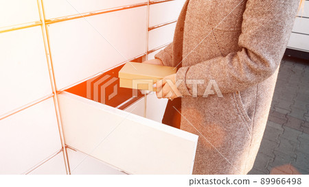 Pickup parcel. Courier box in woman hands at post delivery automat terminal. Self service post terminal and parcel delivery concept. 89966498