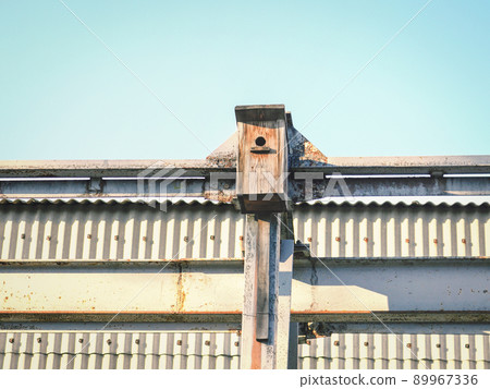 Birdhouse on textured steel wall building at springtime on blue sky background Birdhouse on textured steel wall building at springtime on blue sky background 89967336