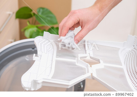 A man takes a lint filter out of dryer and cleans A man takes a lint filter out of dryer and cleans 89967402