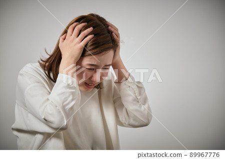 A young woman panicking and holding her head with both hands 89967776